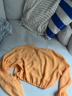 En orange blus från Gina tricot med öppen rygg och knytning, lapparna är kvar och är aldrig använd.