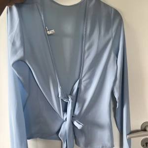 Gullig blå blus  - Blå blus med två knyten på ryggen 