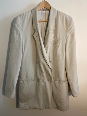 Fin vintage kavaj från Mari Philippe Paris  - Vintage 80-90-talskavaj från Mari Philippe Paris.  Biege,  randigt foder, slag, sprund, fickor, knappar.  Allt sitter som det skall och är helt.  I fodret , uppe vid ena axeln finns ett mini fnas i textil. Se bild. Storl. rymlig D36. Modell har 40 