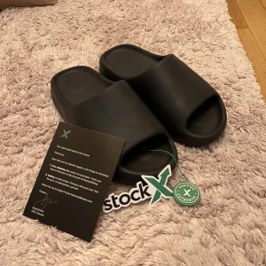 Yeezy Slides Onyx - Svarta Yeezy Slides ”Onyx” - ✅StockX Tags Samt Köparbevis Följer Med Inga märkvärdiga flaws eller skador på dessa, använda fåtal gånger. Rengör dom innan frakt.  Kom Dm för fler bilder