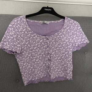 Fin lila blommig t-shirt med knappar. Den är endast använd ett fåtal gånger och är i bra skick!💜