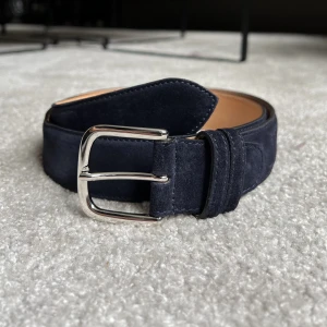 Loro Piana skärp - Mockaskärp från det exklusiva varumärket Loro Piana som är handgjort i Italien. Skärpet är i nyskick. 98 cm långt och 3,5 cm brett.  Nypris 490€  För mer information: https://www.tradera.com/item/608735299