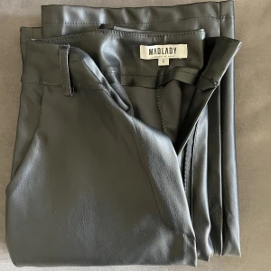 Högmidjade skinnbyxor- hunter black - Högmidjade byxor i fuskskinn, bootcut modell. Sidofickor och bälteshällor.