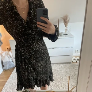 Omlottklänning - Så fin och lyxig omlottklänning från JUST. Storlek XS. Svart med guldiga prickar på och med ett band i midjan. I jättefint skick. Frakt tillkommer💞💞🌸