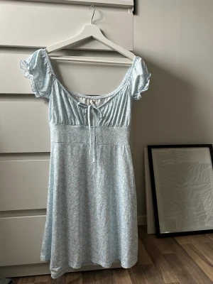 Blommig Klänning  - Drömmens klänning, så gullig. Kommer i från Nellys egna märke NLYtrend. Har bara använt en gång på ett dop. Så väldigt fint skick. Det går även att ha den som off-shoulder