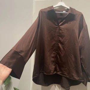  Satinpyjamas  - En brun satinpyjamas från Ginatricot som inte kommer till användning. Väldigt fint skick och väldigt skön material med något vida armar och raka byxor, lite oversized. Ordinarie pris för hela setet 749kr.