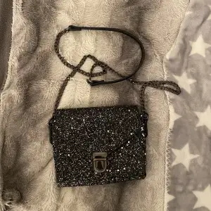 Säljer denna festliga o glittriga väska då den inte kommer till användning längre, väskan är super fin o perfekt storlek för småsaker som mobil, nycklar, laddare mm.🩷
