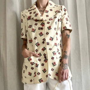 Kortärmad kavaj - Köpt från kända bloggerskan Linn Eklund. Finare vintage med geometriskt mönster. Beige botten. Något markerade axlar i ett lite kraftigare material utan att vara ”tungt”. Stora slag, större fickor och stängs med bruna knappar. Bör verkligen ses irl!