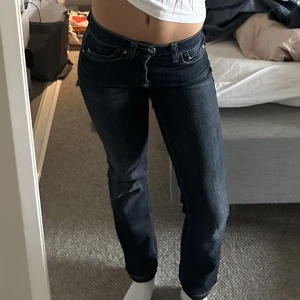 Lågmidjade Jeans - Superfina lågmidjade straight jeans med så fina detaljer på bakfickorna. Storleken är inte synlig men modellen på bilden har vanligtvis strl 27. Gylfen har en tendens att åka ner men har fixat med en nyckelring.
