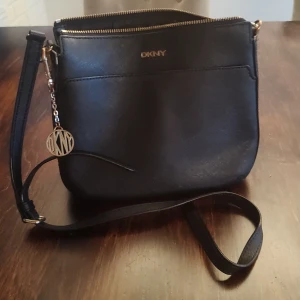 DKNY  - DKNY Axelremsväska Svart med brons metall delar i sin egen signatur Använd skick 