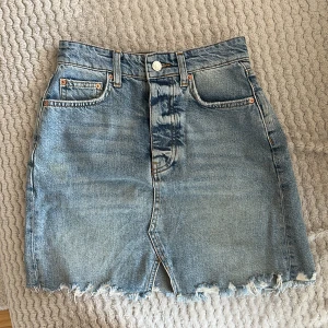 Jeanskjol Gina Tricot  - En väl använd jeanskjol, jätteskön och stretchig i materialet trots att det är jeans. Har några små gulnade fläckar men syns knappt.  Knappar istället för dragkedja som stänger gylfen. 