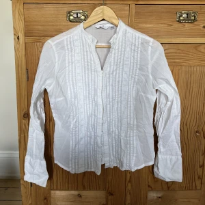 Vit blus - Vit blus med fina detaljer! Går att knäppa hela vägen ner. Står strl 40 men passar som S.