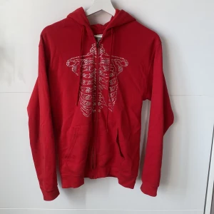 Röd rhinestone hoodie❤️ - Säljer denna fina rhinestone hoodie med trycket av lungor/revben❤️ Fint skick! Hör av dig för fler bilder eller frågor!😇Köpt hos en instagramsida som säljer denna typ av tröjor💗