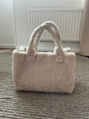 Oanvänd Samsøe Väska - Fluffig väska från samsøe samsøe. Har aldrig använt den så den är i toppenskick! Facket på insidan är löstagbart och blir som en liten nessesär med dragkedja.