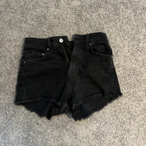 Svarta jeansshorts  - Så snygga jeansshorts med en nästan heltäckande svarta färg. En fransig kant nertill runt hela byxbenet. Så snygga!
