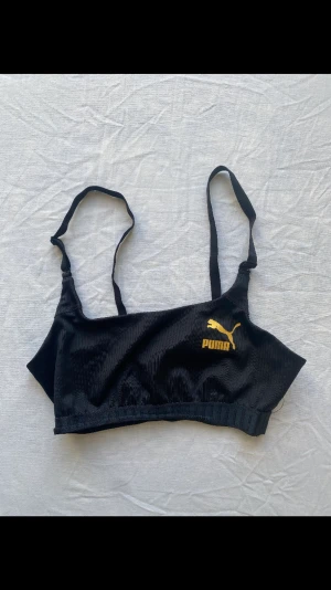 Puma träningstopp - En svart träningstopp från Puma med märket i guld. Tyvärr är lappen avklippt men skulle säga att den är en xs