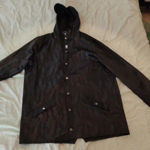 Dropdead regnjacka - Regnjacka från dropdead. Helt svart med fett mönster