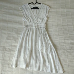 Zara - vit randig klänning/linneklänning, storlek XS - Vit klänning från Zara i linneblandning (52% linne). Snygg design och fint skick. Bara använd en gång. Storlek XS. Andra bilden är lånad (klänningen på bilden är i storlek M).
