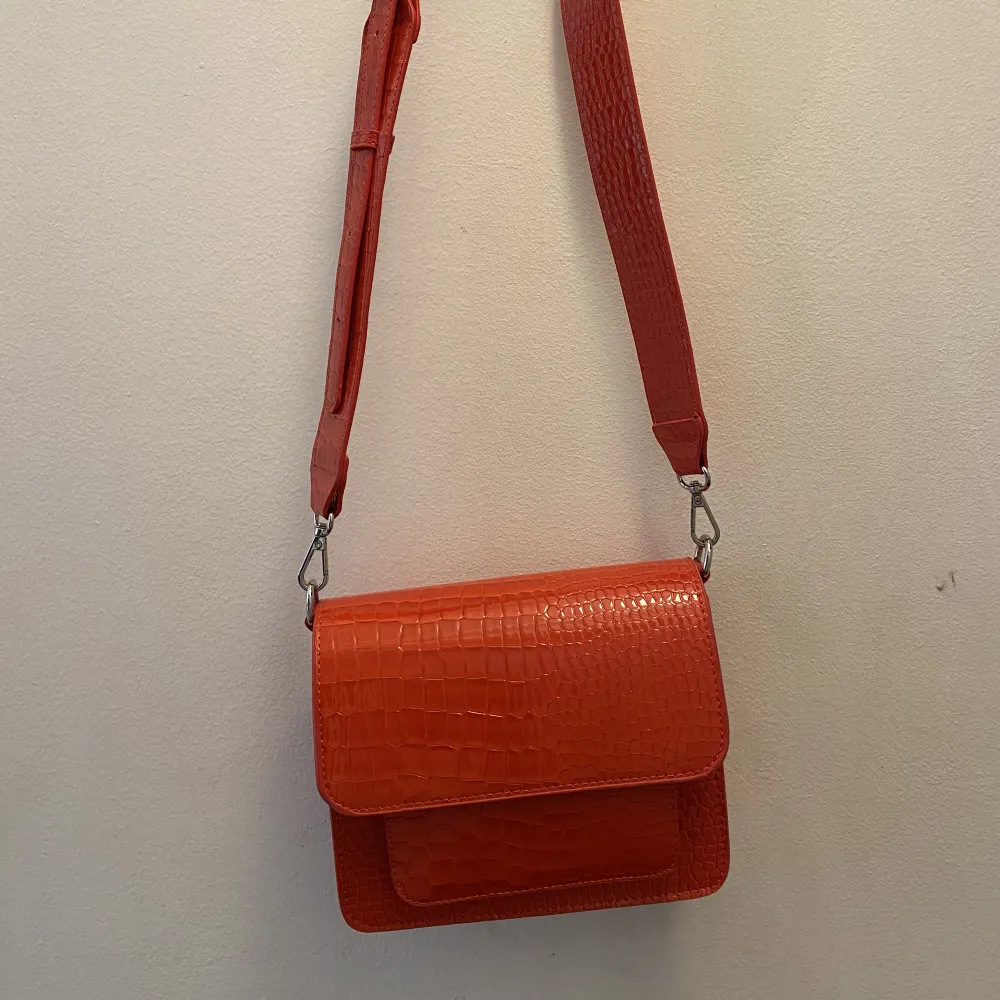 Hvisk väska - CAYMAN POCKET TRACE - RED     Använd en gång så är i nyskick! Ordinarie pris ca 900kr    H17 cm x W21 cm x D9 cm   https://int.hvisk.com/products/cayman-pocket-crossbody-red. Väskor.