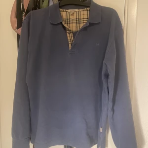 BURBERRY LÅNGÄRMAD PIKÉ - Säljer denna fräscha och snygga långärmade pikéshortan från Burberry. Den är 100% äkta och i väldigt bra skick!! Perfekt nu till lite svalare sommarkvällar😍  Storlek L, passar M också