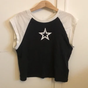 Croppad t-shirt med tryck - Jag säljer denna svarta och vita croppade tröja med en stjärna på.    Priset kan diskuteras! Kontakta vid frågor eller intresse.