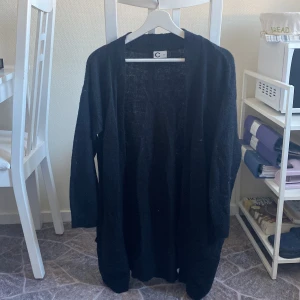 Lång stickad kofta  - En svart, enkel stickad kofta/cardigan som är lång. Passar XS-M skulle jag säga 