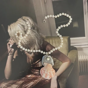 Halsband med snäcka - Halsband av lera med snäcka och pärlor. 