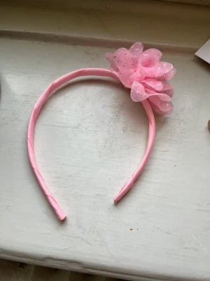 Diadem  - Ett rosa diadem med en rosa blomma. Vet inte vart den är ifrån.  Bra skick har använt den minst 6 gånger. 