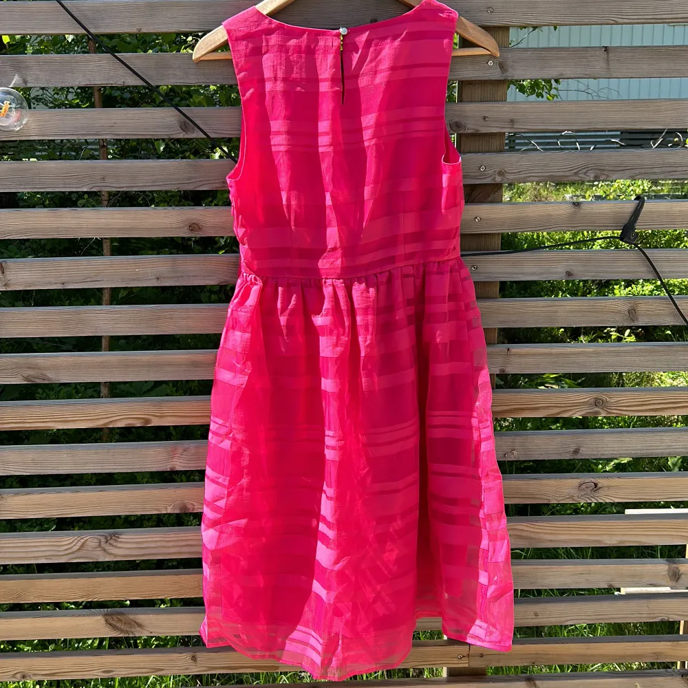 Rosa klänning med utställd kjol från Holly & Whyte/Lindex i stl 36. Stängs med mässingsfärgad knapp i nacke, och har en dold dragkedja på vänster sida.   Perfekt sommarfestklänning!   Aldrig använd, lapparna kvar. . Klänningar.