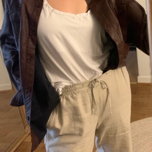 Oanvänd skjorta/jacka i fake-läder vinröd/brunröd strl S/M - En oanvänd oversized brunröd skjorta (kan användas som jacka) från Nelly, är strl 40 så blir oversized om man är S, även om man är M skulle jag säga.