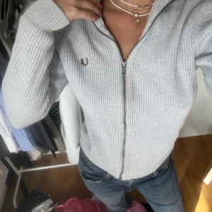 Stickad kofta - Nyskick. Grå stickad kofta med dragkedja från Fred Perry. Storlek S, jag är 173 cm