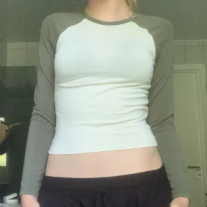 Basebolltröja  - Vit långärmad tröja med mörkgröna armar. Rätt så tajt och kort på mig som är 174 