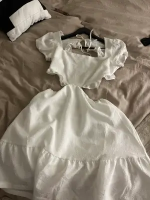 Hej jag säljer en vit klänning som är oanvänd och lappen finns kvar på klänningen, den är öppen i ryggen och vid sidorna av magen men de finns genomskinliga snören som håller upp den.