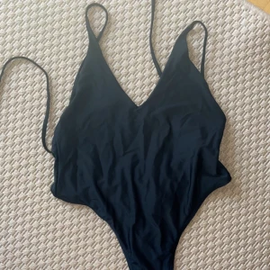 Oanvänd baddräkt - Helt oanvänd baddräkt. Svart string bikini, öppen rygg med hög skärning 