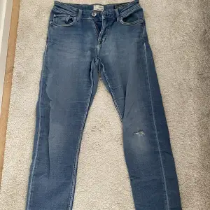 Blåa jeans med fickor både fram och bak och hål på vänstra sidan i Stl 28. Säljer för 100kr. 