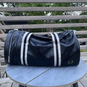 Svart Fred Perry väska  - Säljer en svart Fred Perry väska i läder, storlek one size. Nypris 1200 mitt pris 350kr