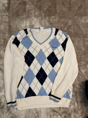 Rutig stickad tröja från urban outfitters  - Stockad tröja med blått rutigt mönster på bröstet. 