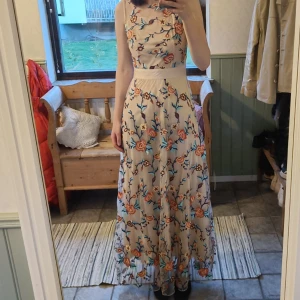 Balklänning - Jättefin beige balklänning med blommor i olika färger. Köpt på Sellpy, endast använd en gång. Mycket bra skick, inga defekter.