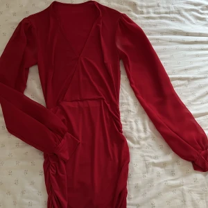 Röd klänning med puffärmar - Röd klänning med puffärmar och V-ring från Nelly, använt 1 gång! 
