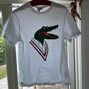 En Lacoste t-shirt i samarbete med Jean-Michel Tixier. Skicket är 6.5/10. Finns lite missfärgning i armhålorna men utöver det i gott skick. Storleken är XL. Tröjan är stilren och passar till i princip allt nu på sommaren. Köptes för 900kr.