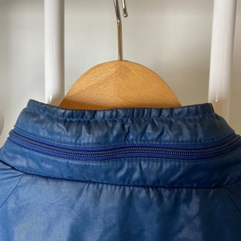 Plastig blå fritidsjacka från klassiska klädföretaget Duckster.  Vintage i mycket fint skick.  Huva i blixtlås vid nacken, innerficka och två fickor med blixtlås. 100 % nylon.. Jackor.