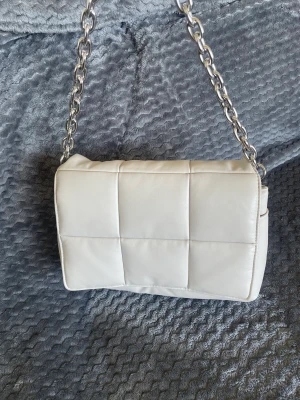 Väska  - En beige väska från hm med silver detaljer, ser helt ny ut och är näst intill oanvänd 