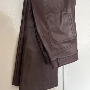 Skinnbyxa - Ankellånga aningen flaired skinnbyxor i strl 38. Aningen små i storlek så passar 36 också. Använda men i väldigt fint skick och i mjuk PU-material. Inte alls klistriga eller plastiga. 