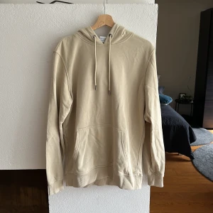 Hoodie Beige - Urban Classics hoodie. Lite nopprig på ryggen men syns knappt.  Passar som L.