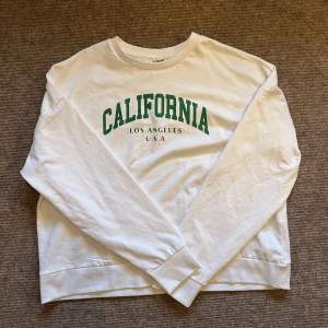 Vit sweatshirt med grön text ”California”. Köpt på Vero Moda men märket är Noisy May. Nästintill oanvänd då den köptes förra sommaren och sen dess bara har provats på en gång. Storlek är M men skulle säga att den passar en S bättre (men båda funkar)