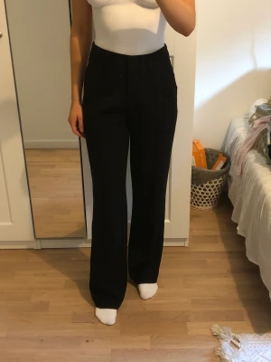 Svarta kostymbyxor  - Svarta kostymbyxor med slits bak i benet 