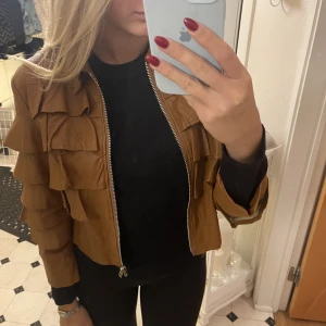 Brun skinnjacka med volang - Brun skinnjacka med volanger. Skinnet är lite skadat inne i jackan men fin på utsidan 💕