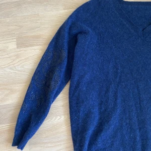 Stickad tröja - Blå tröja med pärlor på armbågarna. 