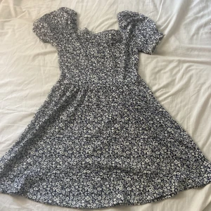 Blå vit blommig klänning från hm - En jätte fin blå klänning med vita blommönster från hm. Storlek 146/152. Lite puffrade i armarna. Använd typ en gång, jätte skönt material.💙 kan sänka priset😌💙