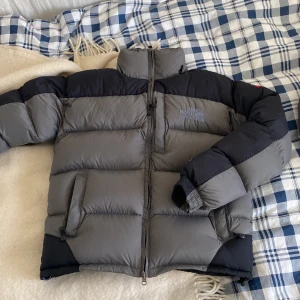 North Face Jacka  - Säljer en The North Face dunjacka i superfint skick, endast ett år gammal❗️Två vanliga fickor och en bröstficka framtill, snygg grå/svart färg och med brun insida. Jackan har en borttagbar luva och är i storlek M! Skriv för mer info!😊💓